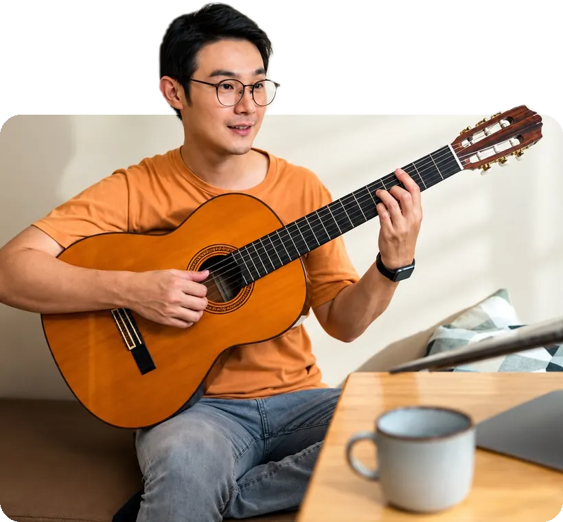 An adult student playing classical guitar at home.