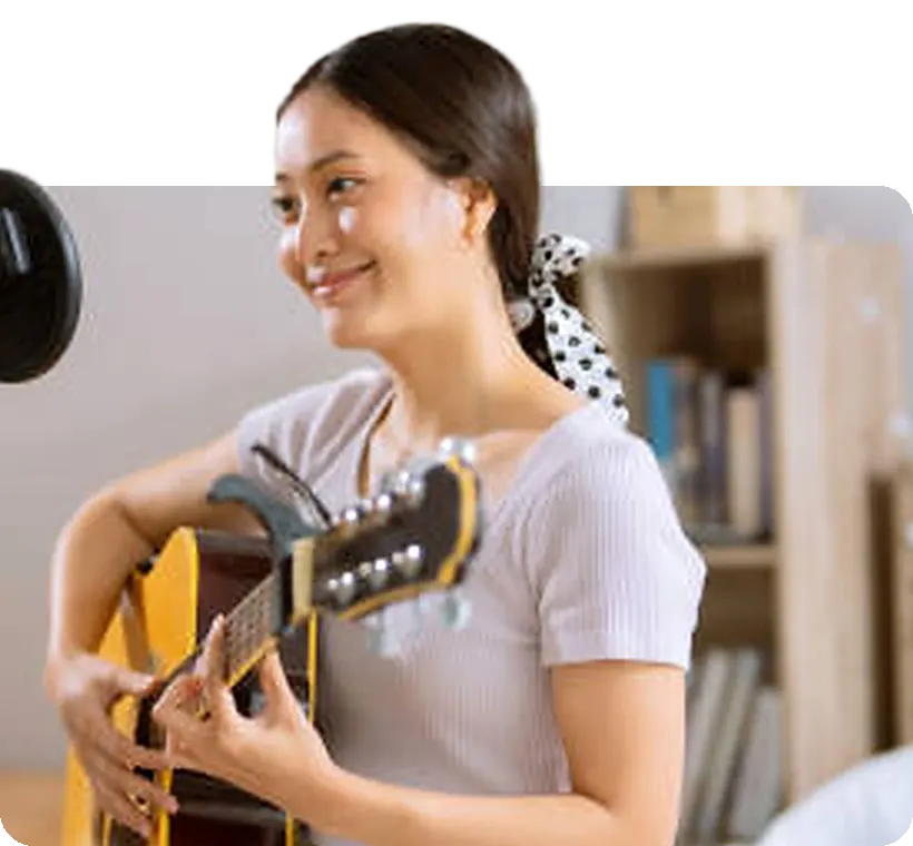 A coach singing with her guitar in her home studio.