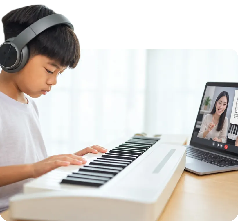 A boy at his keyboard in an online lesson, his coach on the laptop.