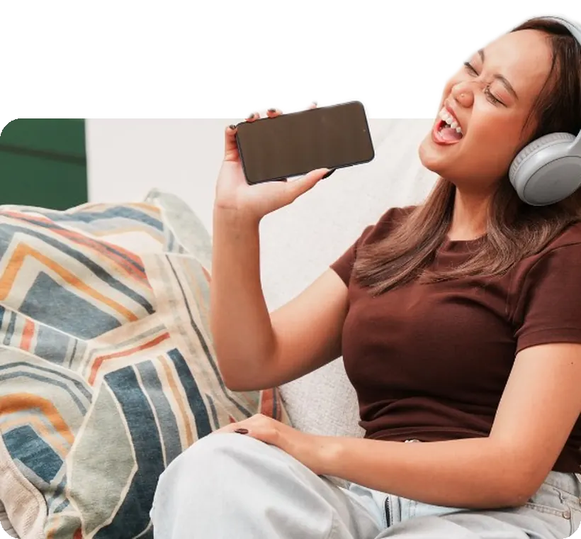 A student on the couch with her phone, singing along.
