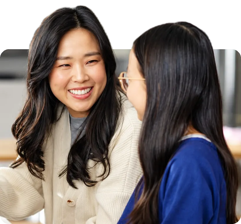 A piano coach smiling at her student at the piano.