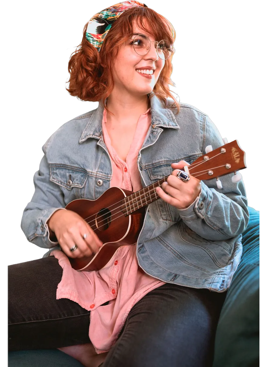 A music coach smiling as she plays the ukulele