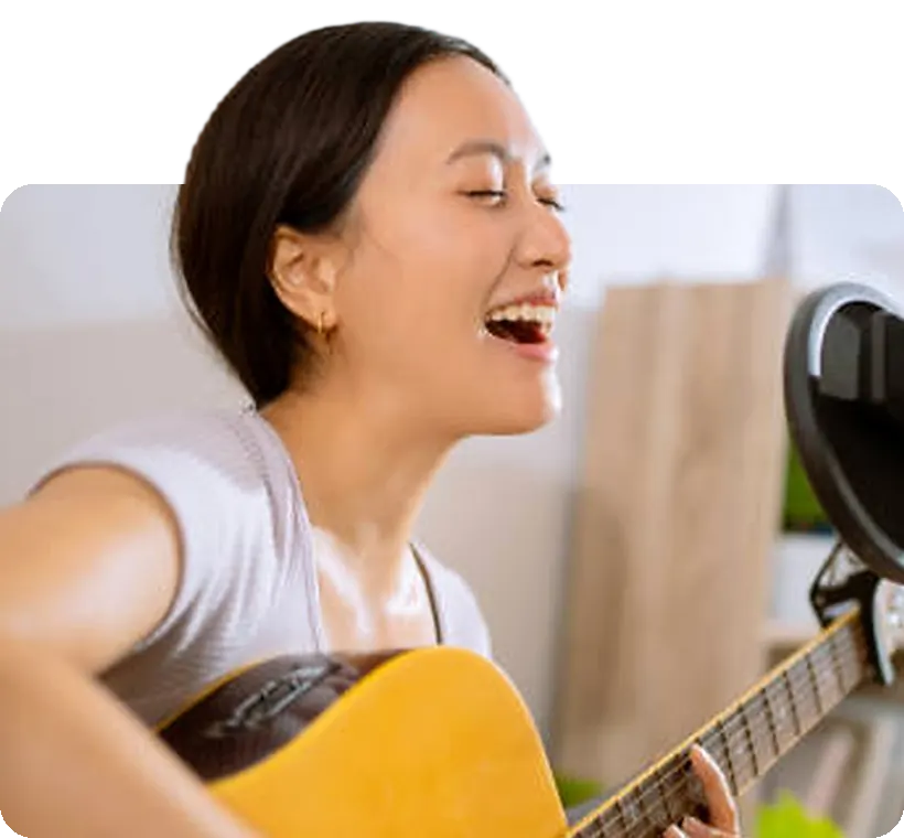 A student singing and playing guitar at home.